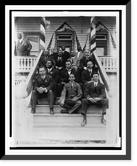 Booker T. Washington, seated on steps, with group of other men, outside of building, Vintage Poster