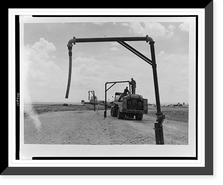 View of tank truck getting fuel from pipe to refuel airplane(?), Italy, Historic Reproduction