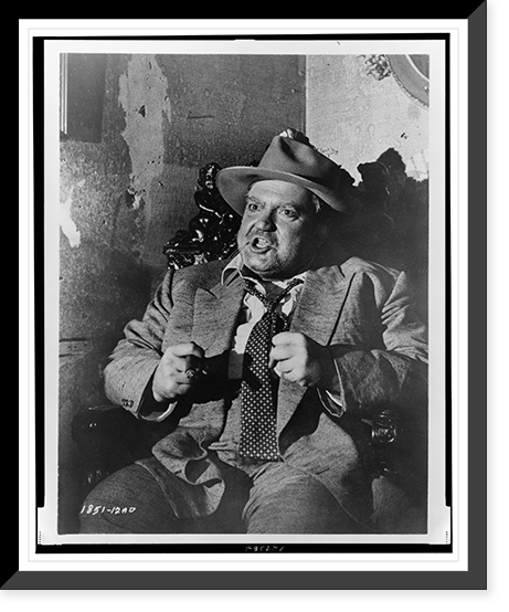 Orson Welles, three-quarter length portrait, seated, facing front, with his fists clenched before him in a scene from the movie Touch of evil"", Vintage Print