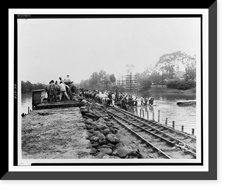 Workers unloading sandbags from flatbed railroad car, while others are building a levee, partially submerged electric power line poles on right.Ewing, Inc., Baton Rouge. - 2 Vintage Wall Art Prin