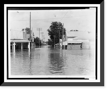 Historic Framed Print, [Floodwaters inundate the street and stores in a business district],  17-7/8" x 21-7/8"