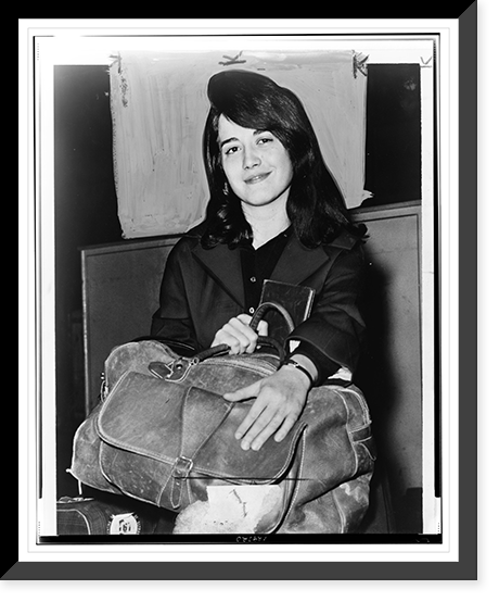 Martha Argerich, full-length portrait, facing front, seated, holding luggage, at Pier 86, after having arrived on the liner Constitution.World Telegram & Sun photo by Dick DeMarsico. Antique Wall