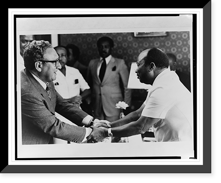 Liberian president William R. Tolbert and Henry Kissinger clasp hands across a table as others look on Classic, Historic Print