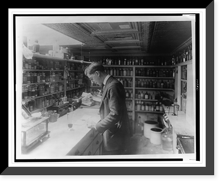 Pharmacist at People's Drug Store, No. 5, 8th and H Streets, N.E., Washington, D.C., looking at prescriptions(?) on the counter in room lined with shelves of pharmacy bottles Vintage Wall Art Pri