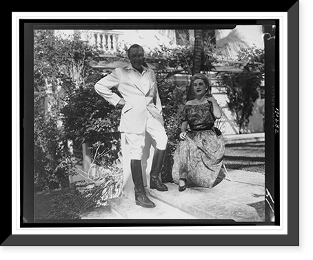 Barbara Hutton seated, with her husband Porfirio Rubirosa standing beside her, on steps outside house, Historic Reproduction