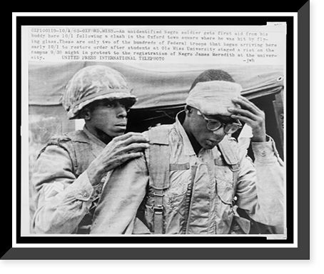 Historic Framed Print, An unidentified Negro soldier gets first aid from his buddy. following a clash in the Oxford town square where he was hit by flying glass,  17-7/8" x 21-7/8"