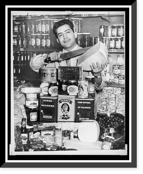 Historic Framed Print, Gus Marris is shown with a large display of Greek foods at the Couphopoulos Delicatessen at 306 W. 40th St..World Telegram & Sun photo by Fred Palumbo.,  17-7/8" x 21-7/8"