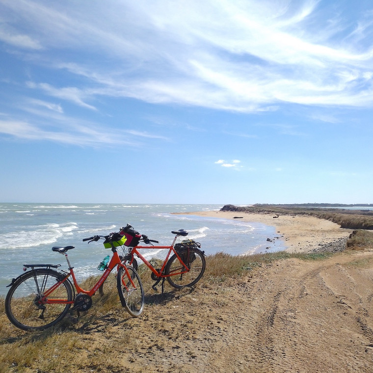 Two touring bikes with panniers parked on a sandy beach on the Salento coast, Puglia, Italy