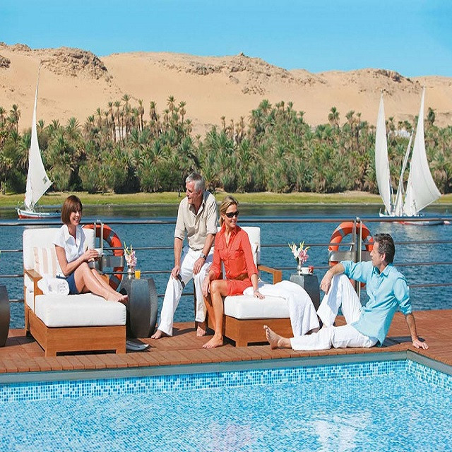 Guests relaxing on a Nile cruise deck as feluccas pass, Egypt