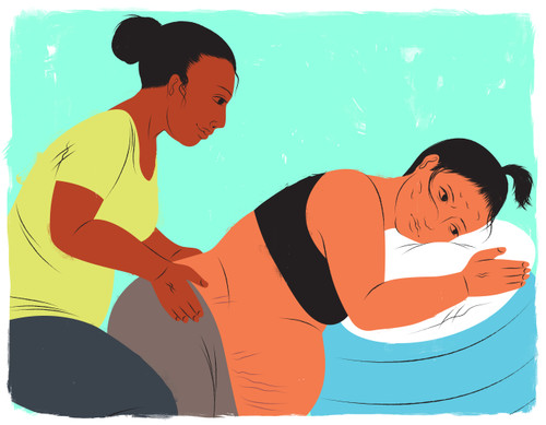 Mother leaning against birthing ball while doula applies pressure