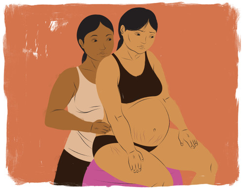 Doula behind mother sitting on birthing ball