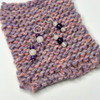 rose quartz and amethyst stitch markers with rounded beads on a section of knitted fabric