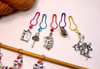 Close-up of Alice in Wonderland beaded row counter chain on bamboo knitting needle, highlighting numbered beads 1–9 with colourful seed beads and enamel Alice and White Rabbit charms