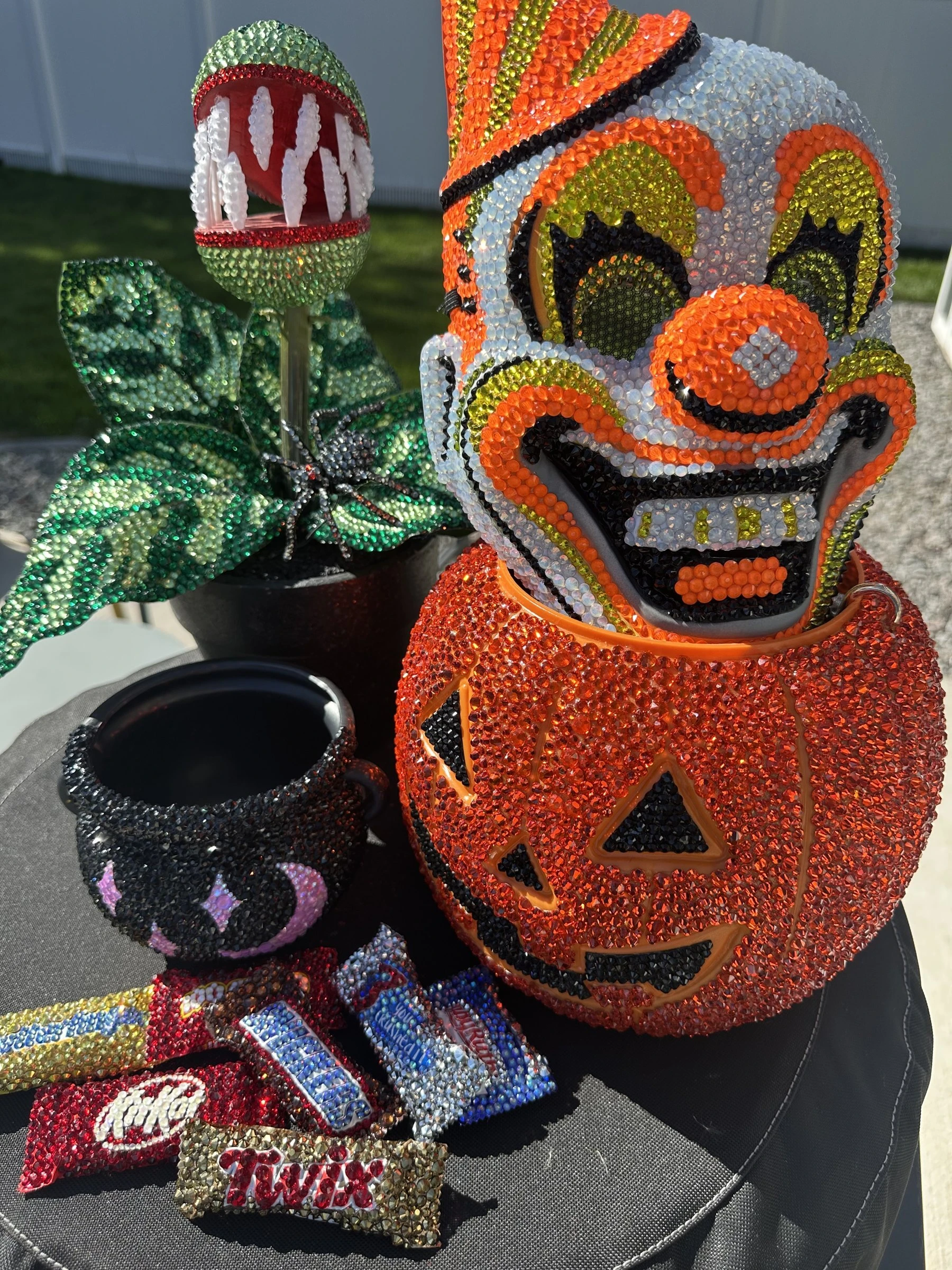 Crystal-covered Halloween decor by @addsomespark: a jack-o'-lantern trick-or-treat bucket topped with a clown mask, a cauldron, a piranha plant, and candy bars