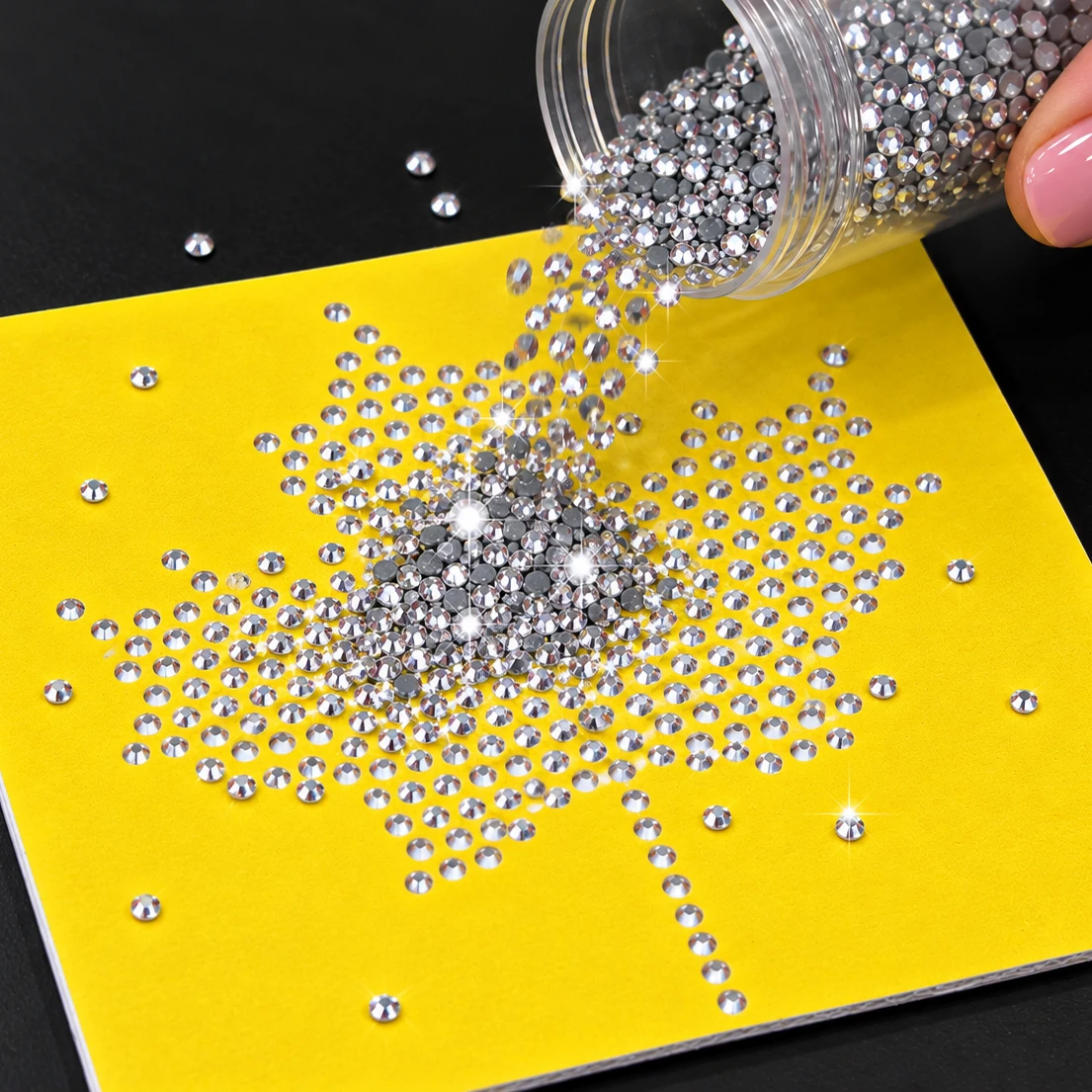 Pouring clear hotfix rhinestones over a yellow maple leaf rhinestone template