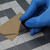 Ergonomic Utility Blade Tool demonstrated cutting through thick cardboard effectively, easily held in hand by user ergonomically.