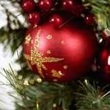 Red glitter-starred ornament on a green pine branch — scent inspiration for Scents of the Season fragrance oil