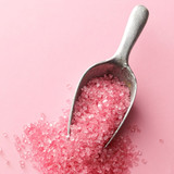 Metal scoop of pink sugar crystals on pink — scent inspiration for Pink Sugar fragrance oil