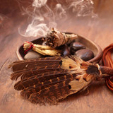 Smoking bundle in a bowl with feathers on dark wood — scent inspiration for Indian Sandalwood fragrance oil