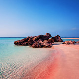 Pink-tinged sandy beach with rocks and turquoise water — scent inspiration for Pink Sands fragrance oil