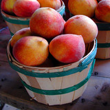 Wooden baskets of red-yellow peaches on wood — scent inspiration for Georgia Peach fragrance oil