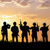 Silhouetted armed soldiers against an orange sunset sky — scent inspiration for Dauntless fragrance oil
