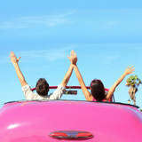 Couple raising arms in a pink convertible, blue sky — scent inspiration for Endless Weekend fragrance oil