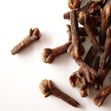 Scattered whole dried cloves on white — scent inspiration for Clove fragrance oil