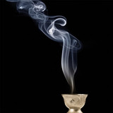 White smoke rising from a small brass incense holder — scent inspiration for Nagchampa fragrance oil
