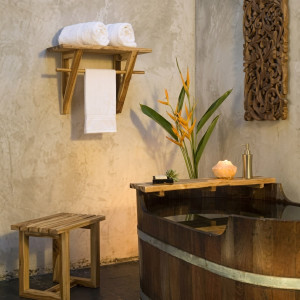 Wooden bath tub, towel rack, and salt lamp against stucco — scent inspiration for Teak Bamboo fragrance oil