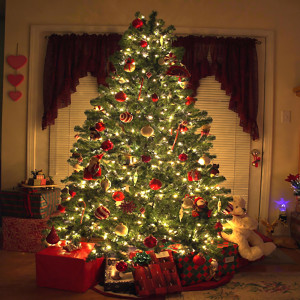 Lit decorated Christmas tree with gifts at night — scent inspiration for Christmas Tree fragrance oil