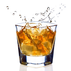 Amber liquid splashing in an ice-filled glass on white — scent inspiration for Amaretto fragrance oil