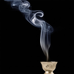 White smoke rising from a small brass incense holder — scent inspiration for Nagchampa fragrance oil