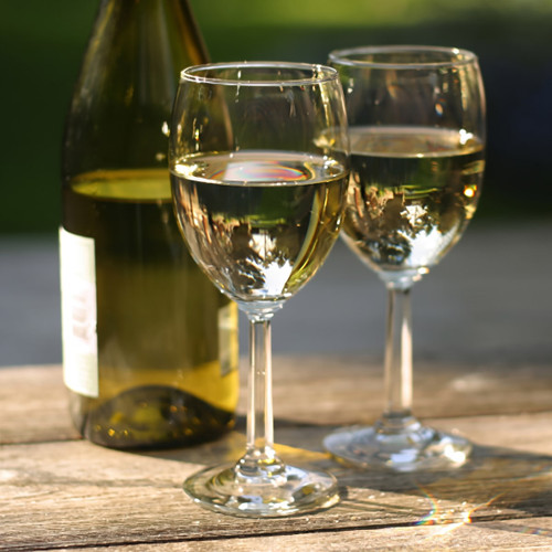 Two glasses of white wine with bottle on wood table — scent inspiration for Chardonnay fragrance oil