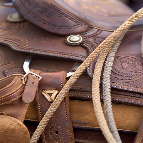 Brown tooled leather saddle with straps and rope — scent inspiration for Leather fragrance oil