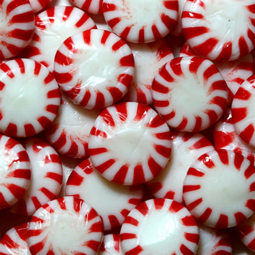 Pile of red-and-white striped round peppermint candies — scent inspiration for Peppermint fragrance oil
