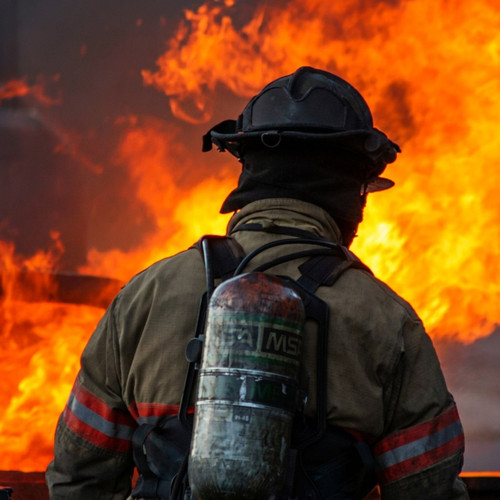 Firefighter in gear silhouetted against orange flames — scent inspiration for Rugged fragrance oil