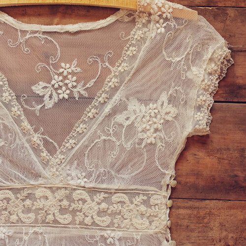 Cream lace dress on hanger against rustic wood planks — scent inspiration for Western Lace fragrance oil