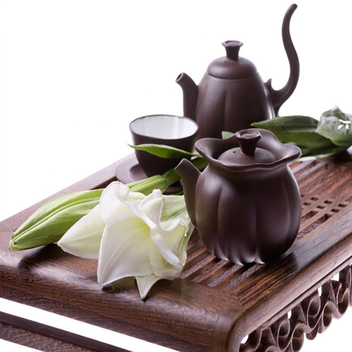 Brown clay teapot set with a white flower on a tray — scent inspiration for White Tea & Ginger fragrance oil