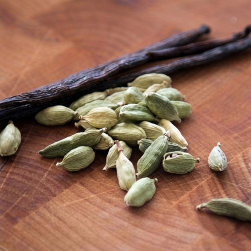 Green cardamom pods and vanilla beans on wood — scent inspiration for Vanilla Cardamom fragrance oil
