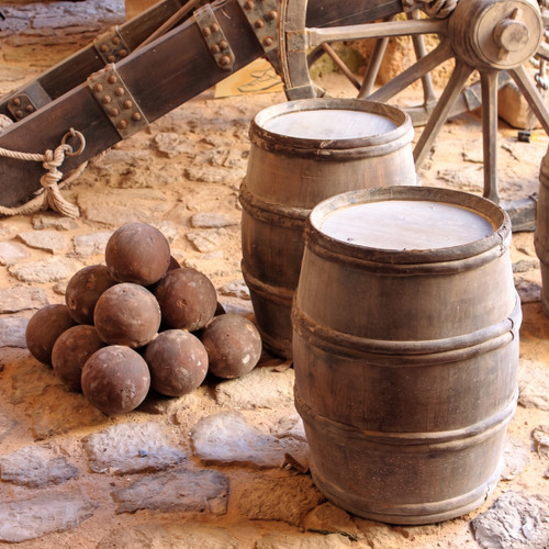 old wooden barrels, stacked cannonballs and cannon on stone — scent inspiration for Gunpowder fragrance oil