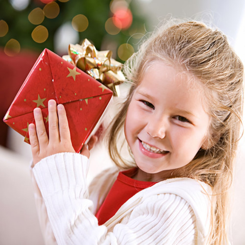 Smiling blonde girl holding a red gold-bowed gift — scent inspiration for Christmas Cheer fragrance oil