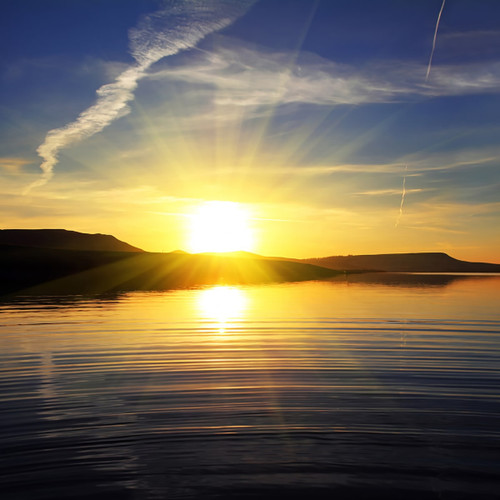 Bright sun rising over calm water and hills — scent inspiration for Early Sunrise fragrance oil