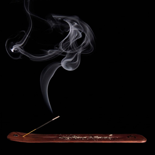 Smoking incense stick on a wooden holder, black background — scent inspiration for Patchouli fragrance oil