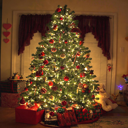 Lit decorated Christmas tree with gifts at night — scent inspiration for Christmas Tree fragrance oil