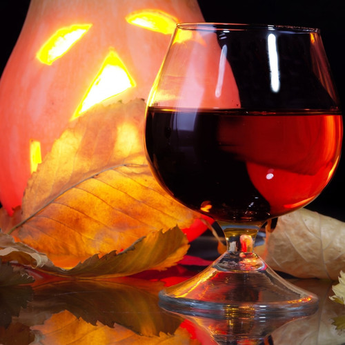 Brandy snifter of red liquid beside a glowing carved pumpkin — scent inspiration for Drunken Punkin fragrance oil