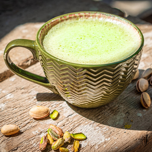 Green frothy latte in textured mug with pistachios — scent inspiration for Pistachio Latte fragrance oil
