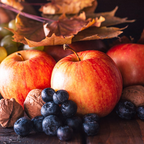 Red apples, blueberries, walnuts, and autumn leaves on dark wood — scent inspiration for Apple Berry Harvest fragrance oil