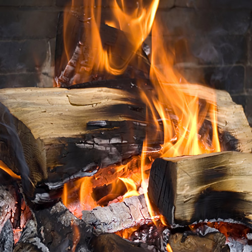 Burning logs with orange flames in a brick fireplace — scent inspiration for Firewood fragrance oil