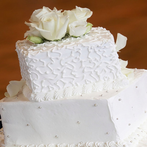 White tiered cake with piped icing and white roses — scent inspiration for White Cake fragrance oil
